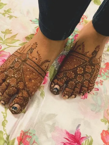 This foot mehendi features elegant peacock motifs on the top of the feet, with delicate patterns extending to the toes.