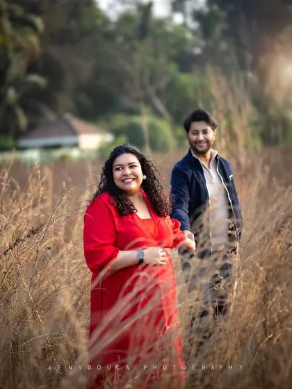 A joyful, candid moment of the couple walking hand-in-hand through a field of tall grass during the golden hour.