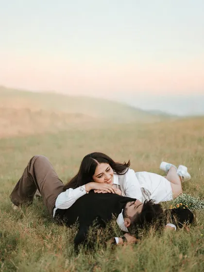 A romantic and peaceful moment with Monil and Charmi lying in a grassy field at dusk. The soft light and natural setting make this a beautifully tender portrait.