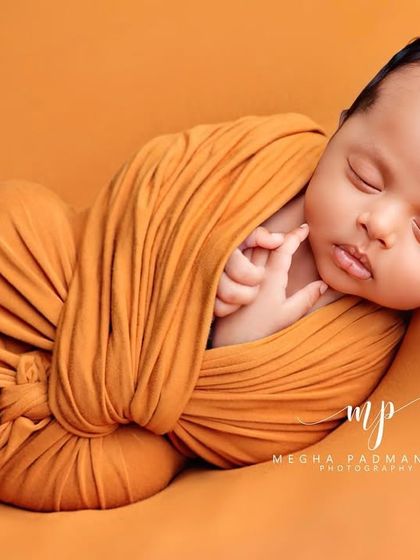 A newborn wrapped in a warm, mustard-yellow swaddle. This 'potato sack' pose is a client favorite.