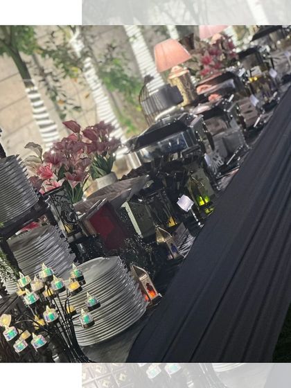A long shot of an outdoor buffet line at night. The elegant setup with black linens and decorative elements creates a sophisticated ambiance for any evening event.