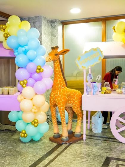 A pair of pastel-colored food carts serving snacks and treats, flanked by a life-sized giraffe prop.