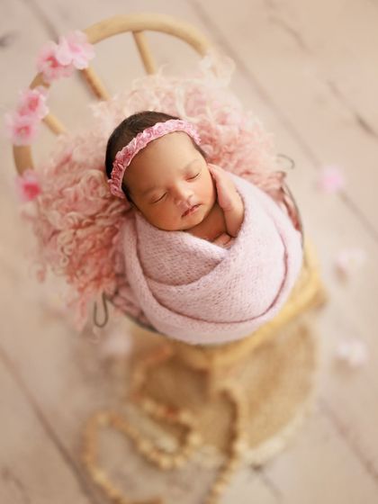 Pretty with pink and sakura blossoms. This setup uses a soft pink wrap and headband, with delicate petals scattered around for a lovely springtime feel.