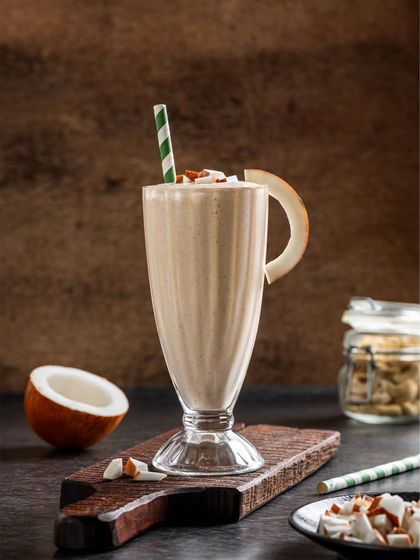 A coconut-flavored milkshake, garnished with a slice of dried coconut, offering a tropical vibe.