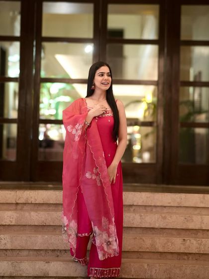 A full-length shot of the pink kurta set on a staircase, showing its elegant and traditional design.