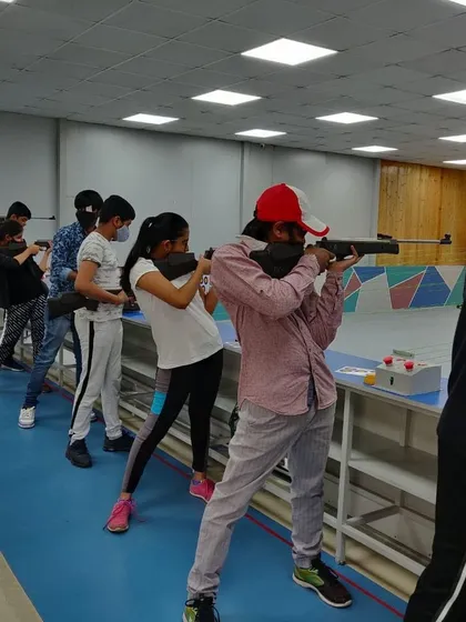 A line of young campers learning to handle the open sight rifle. This is a great starting point for beginners to understand the basics of aiming and shooting posture.