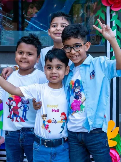 A group of boys smiling and posing for the camera at our outdoor Holi event.