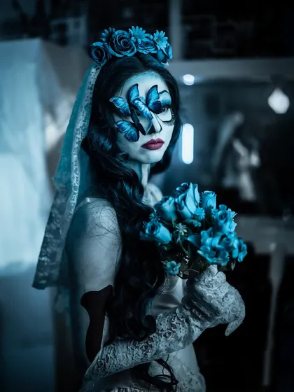 A portrait of the Corpse Bride with her bouquet of blue roses. The butterfly details on the face add a touch of delicate artistry to this spooky look.