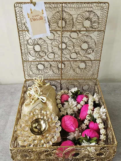 A beautiful gold wire mesh box filled with a floral diya, potlis, and other festive decorations. This hamper is a wonderful example of how I curate items to create a cohesive and luxurious gift.