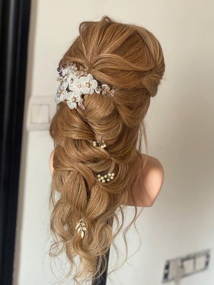 A romantic and whimsical hairdo created on a mannequin. This intricate braid combines different techniques and is adorned with beautiful floral and pearl accessories.