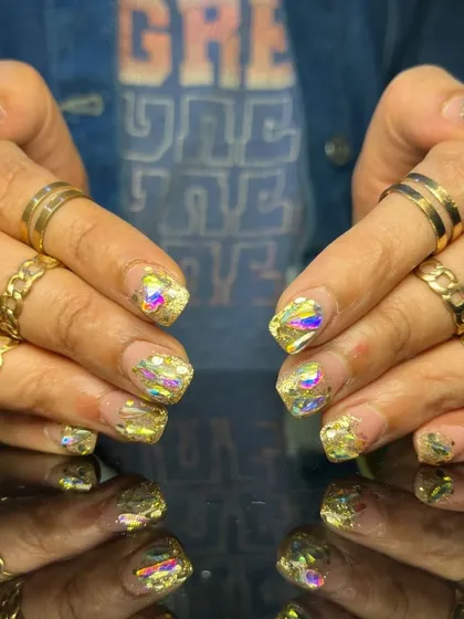 A bold and glamorous set of short, square nails with a shattered glass effect using iridescent gold foil.