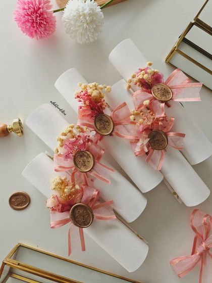 The finished Devanagari wedding invitations, rolled into scrolls and adorned with dried flowers, ribbons, and wax seals. Despite a setback, I remade each one to ensure they were perfect.