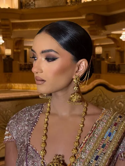 A dramatic and artistic reception look. The sharp, extended winged liner and bronzed skin create a powerful statement, complemented by the traditional gold jewelry.