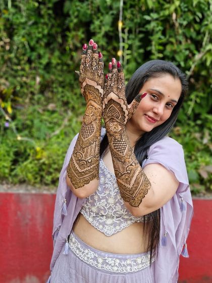 A happy client at her engagement, her hands adorned with a beautiful, intricate design that extends up her arms.