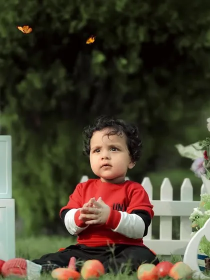 A moment of wonder amidst the birthday fun. This little boy is surrounded by butterflies and flowers in a beautiful garden setup for his first birthday.
