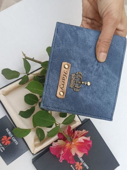 A personalized denim wallet in a lovely blue shade, held with a rose to showcase it as a romantic and thoughtful gift.