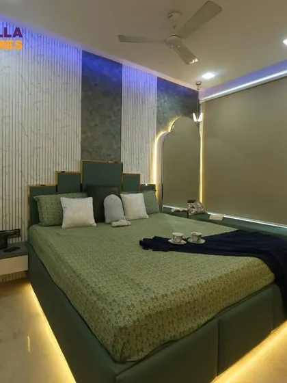 A full view of a master bedroom with a unique green-and-gold headboard and ambient lighting. The large window has a comfortable seating nook, perfect for enjoying the view.