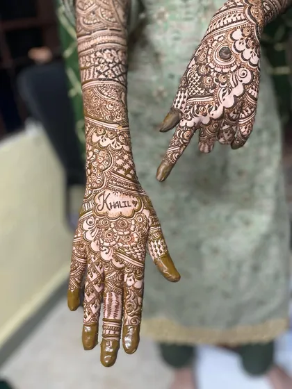 Hiding the groom's name is a fun tradition. In this design, the name 'Khalil' is written in a heart shape on the palm, surrounded by intricate patterns.
