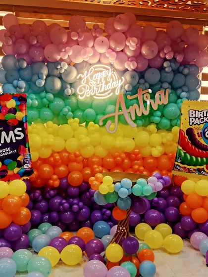 A vibrant and fun Cadbury Gems themed party. The wall of rainbow-colored balloons and oversized Gems packet props make for an unforgettable photo backdrop.