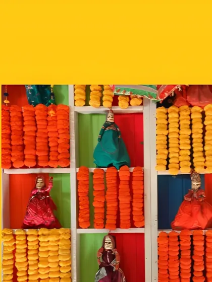 A unique backdrop for a Haldi ceremony, with shelves holding traditional handcrafted dolls and separated by bright orange and yellow marigold garlands.