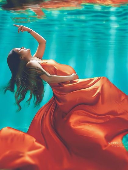Another stunning "underwater" creation. The mother-to-be, in a vibrant orange gown, appears to be gracefully floating in turquoise water.