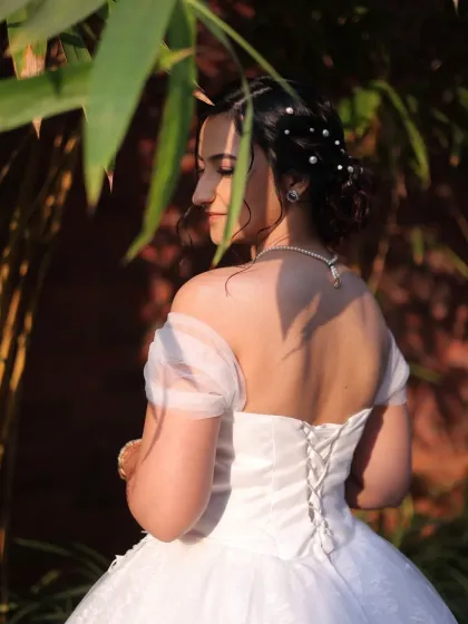 The back view of a Christian bride's gown and hairstyle. The corset lacing of the dress is complemented by a soft, romantic updo with pearl accents, creating a look of timeless grace.