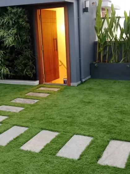 A complete terrace transformation featuring a lush artificial grass lawn with integrated stone pavers for a clean, modern pathway. This installation also includes a vertical garden accent wall by the entryway, creating a welcoming and vibrant outdoor living space that is entirely maintenance-free.