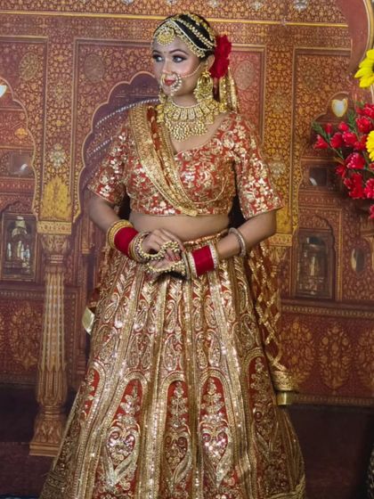 A classic red and gold bridal lehenga with heavy sequin work. The traditional backdrop highlights the royal feel of this rental outfit.