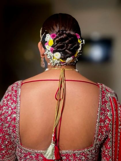 A beautifully detailed shot of a twisted bridal bun, decorated with a mix of yellow, white, and purple flowers. The intricacy of the twists adds so much texture.