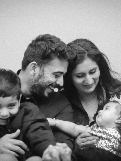 A tender black and white photo of the family interacting, with the baby girl reaching for her big brother.