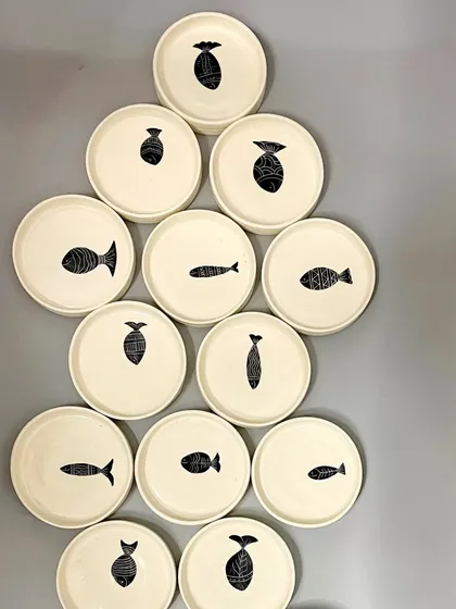 Dive into dining with style. These hand-painted plates each feature a unique fish motif, created using the Sgraffito technique. They are perfect for adding a touch of coastal charm to your meal.