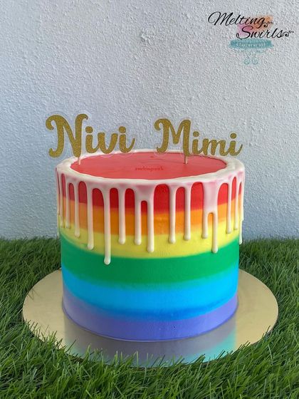 A vibrant rainbow drip cake made for a twin birthday celebration. This cake is rainbow inside and out, frosted with whipped cream and topped with a clean white chocolate drip.