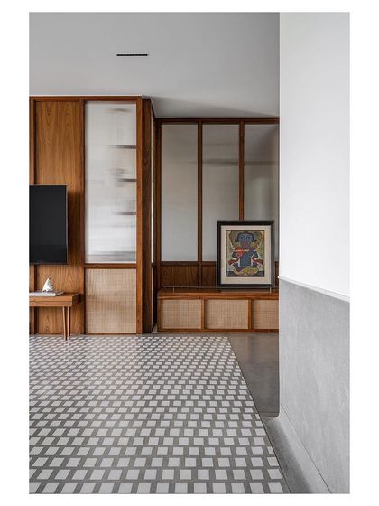 A TV and media unit integrated into a wall of teak and rattan paneling.