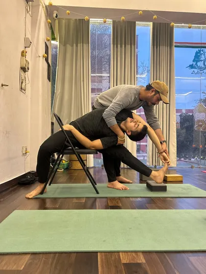 Using props to explore deeper stretches. My Guru assists me in a seated side bend, teaching me how to use tools to work on flexibility safely and effectively.