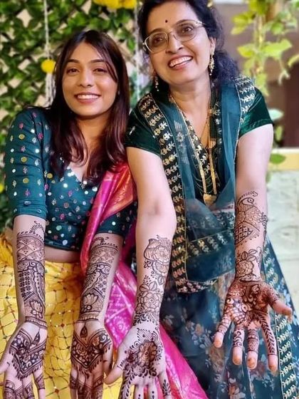 A heartwarming photo of a daughter and mother showing off their matching mehndi designs. We love creating art for the whole family.