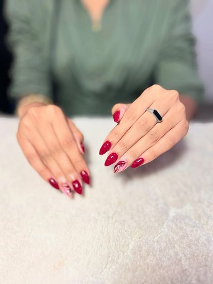 A classic red almond set with a subtle marble accent nail. This shows how to add a touch of trendiness to a timeless look.