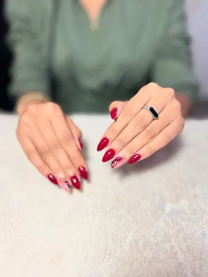 A classic red almond set with a subtle marble accent nail. This shows how to add a touch of trendiness to a timeless look.