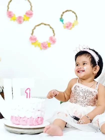 A sweet moment just before the smash. This little girl, dressed in a beautiful sequin dress, smiles beside her first birthday cake in our studio, ready for her celebratory photoshoot.