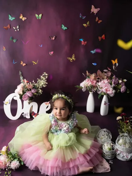 A dreamy "ONE-derland" for a special birthday girl. This enchanting setup features a rich purple backdrop, flowers, and magical butterflies for a whimsical first birthday shoot.