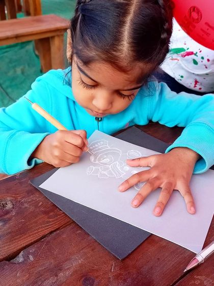 A young girl carefully tracing a snowman design for a parchment craft activity at our Christmas workshop.