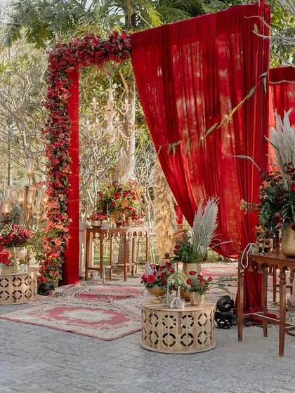 The entrance vignette for the 'Regal Rustic Reverie' wedding, featuring rich red drapes, rustic rugs, and ornate tables, setting a luxurious tone from the start.