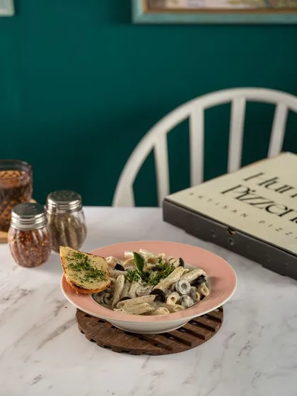 A creamy bowl of pasta from The Humble Pizzeria. The soft lighting and simple plating create an inviting and comforting image, perfect for showcasing a classic cafe dish.
