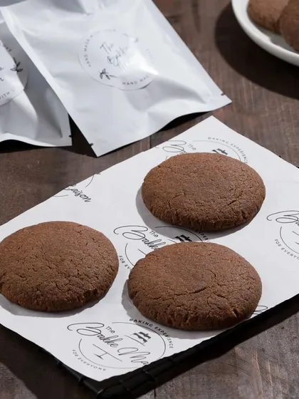 Simple chocolate cookies on branded butter paper. This minimalist shot is effective for showcasing the product and branding together.