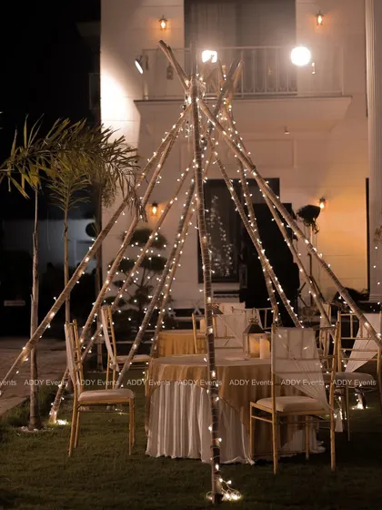 Another look at the fairy-lit teepee dining setup, this time with a grand villa in the background, showing how we can transform any space into a magical setting.