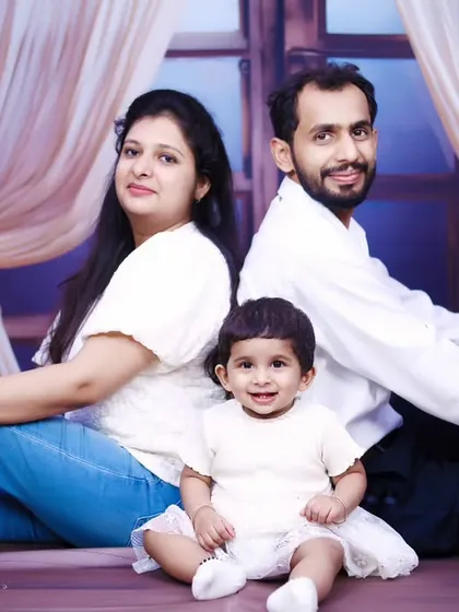 A classic seated family portrait with a smiling baby girl at the center.