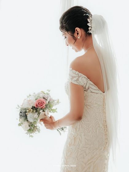 A beautiful shot of the back of the bride's gown, showcasing the delicate buttons and the elegant line of her veil.