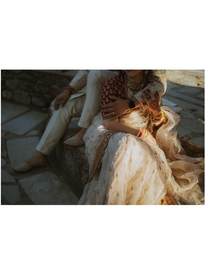 A tender and quiet moment stolen away during the wedding festivities, with the bride resting in the groom's lap.