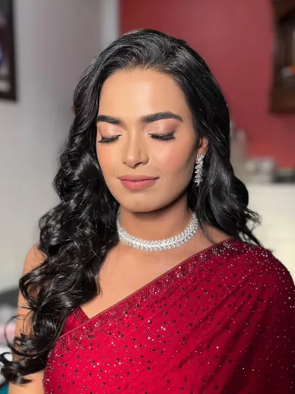 A close-up of the eye makeup, showing the soft pink and brown tones that complement the red saree beautifully.