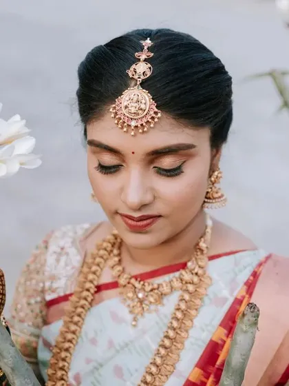 A beautiful close-up of the bride, Aishwarya, on her big day. The soft focus on the white flowers in the foreground adds a delicate and artistic touch.