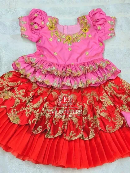 A flat-lay of the red and pink layered Banarasi lehenga, showing the intricate gold work and tiered design.